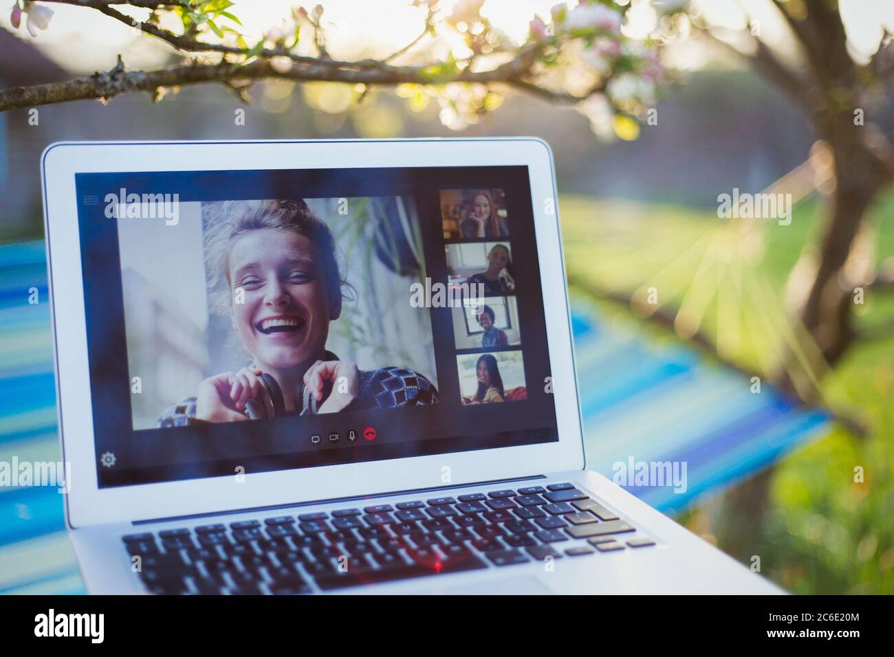 Friends video chatting on laptop screen in sunny garden Stock Photo