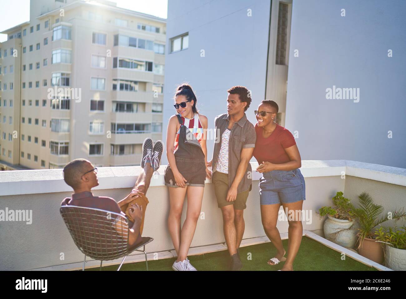 Young friends hanging out on sunny urban rooftop Stock Photo