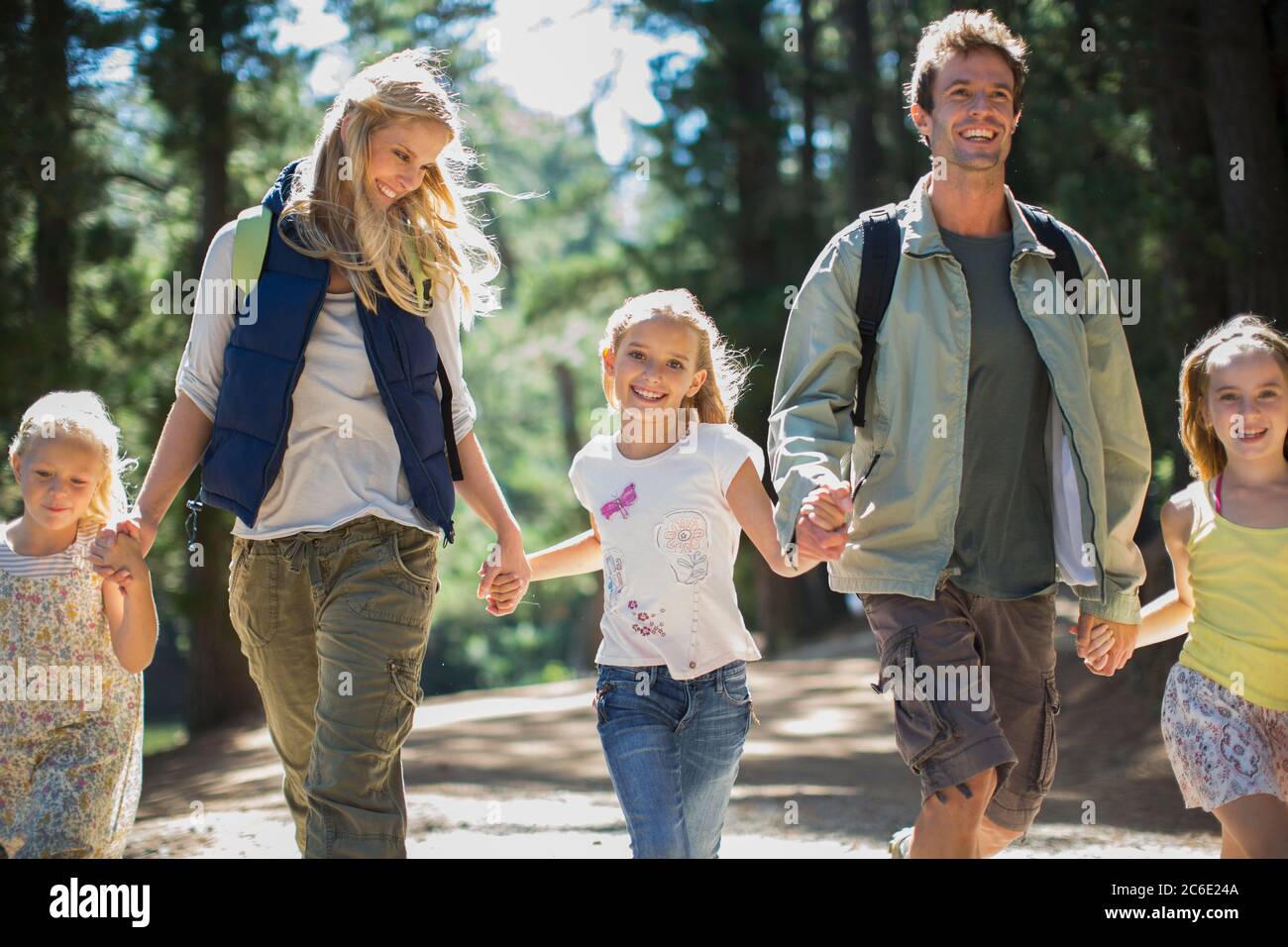 Smiling family holding hands and walking in woods Stock Photo