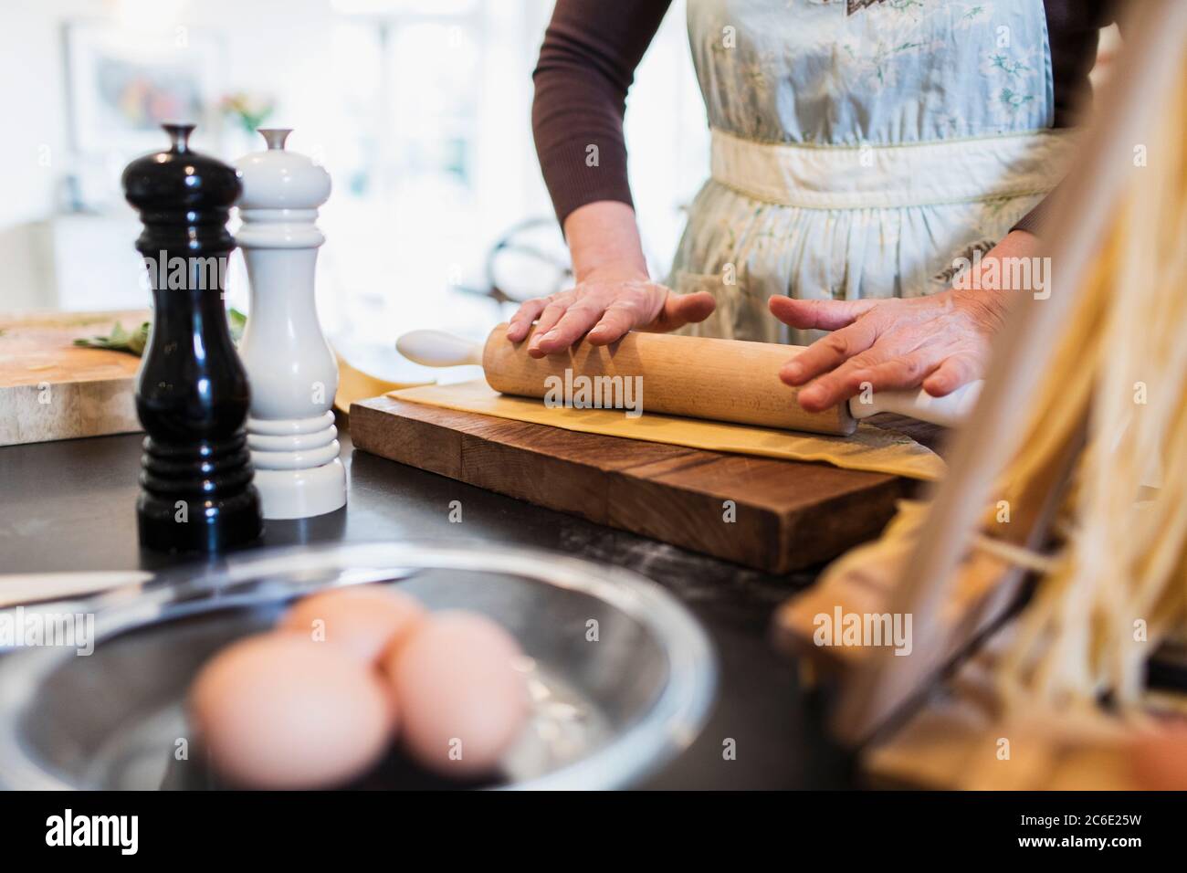Woman rolling dough with rolling pin in kitchen Stock Photo