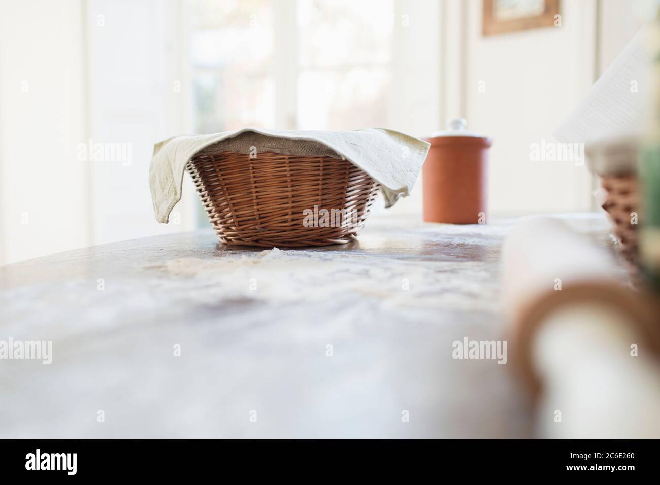 Bread dough proofing in basket on kitchen counter Stock Photo