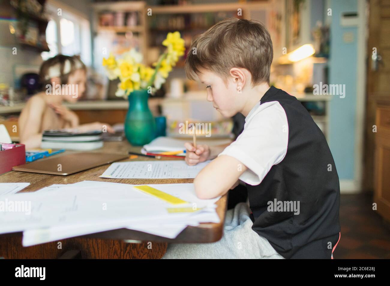 Focused boy homeschooling at dining table Stock Photo