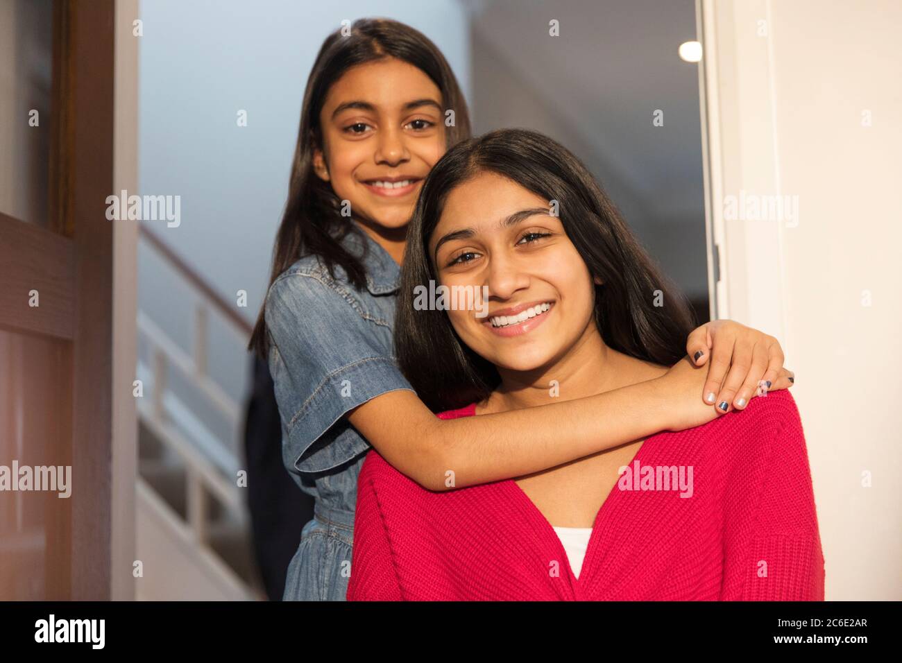 Portrait happy sisters hugging in doorway Stock Photo
