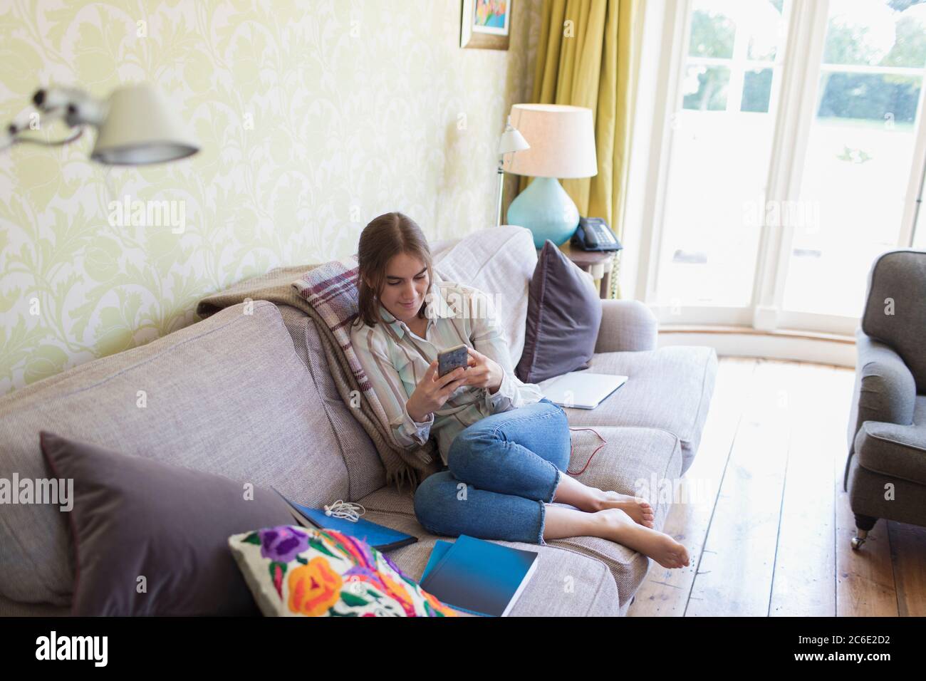 Teenage girl using smart phone on living room sofa Stock Photo - Alamy