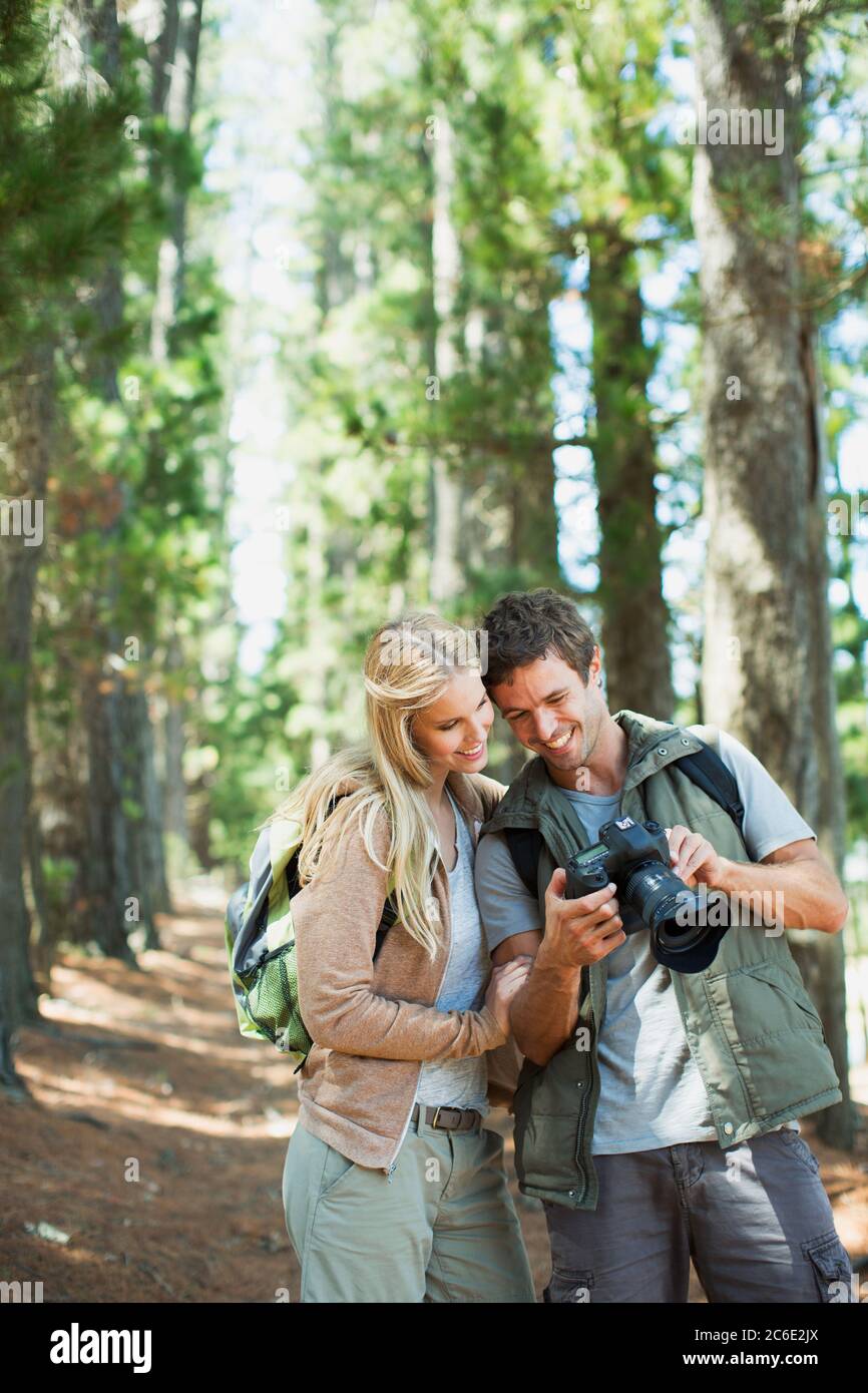 Smiling couple looking at digital camera in woods Stock Photo