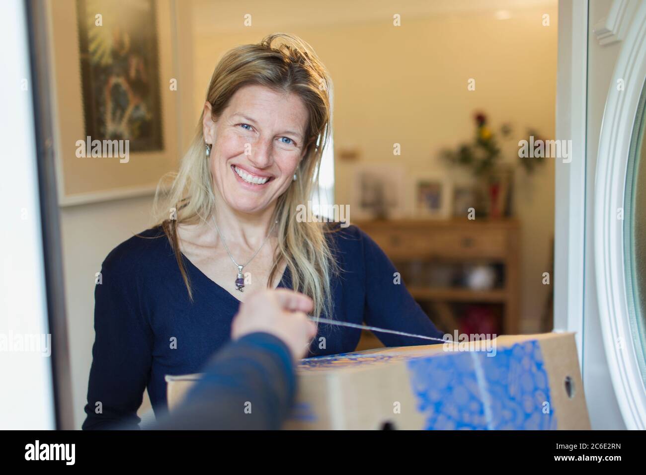 Portrait smiling woman receiving delivery at front door Stock Photo