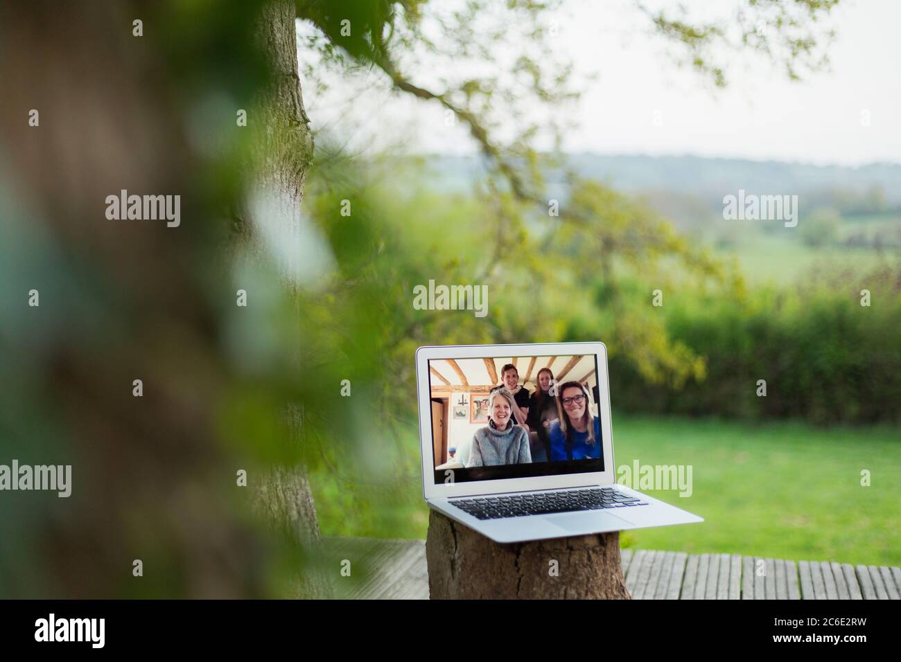 Family video chatting on laptop screen on balcony Stock Photo