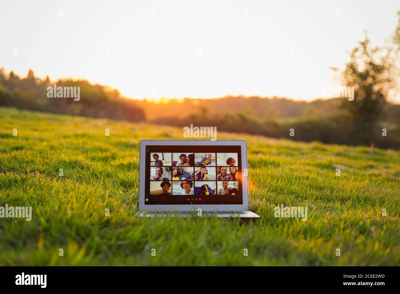 Friends video chatting on laptop screen in sunny grass Stock Photo