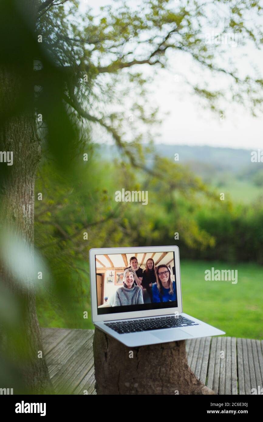 Family video chatting on laptop screen on balcony Stock Photo