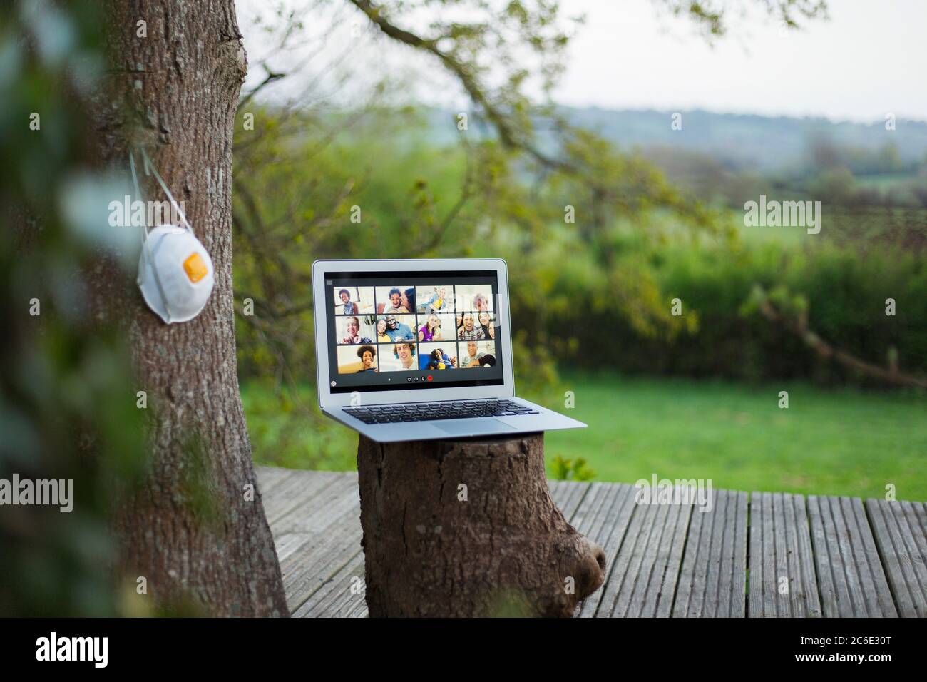 Face mask hanging next to video chat on laptop screen on balcony Stock Photo