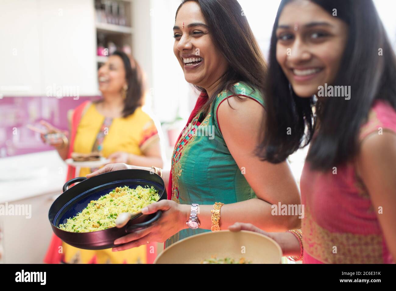 Happy Indian women in saris cooking food in kitchen Stock Photo