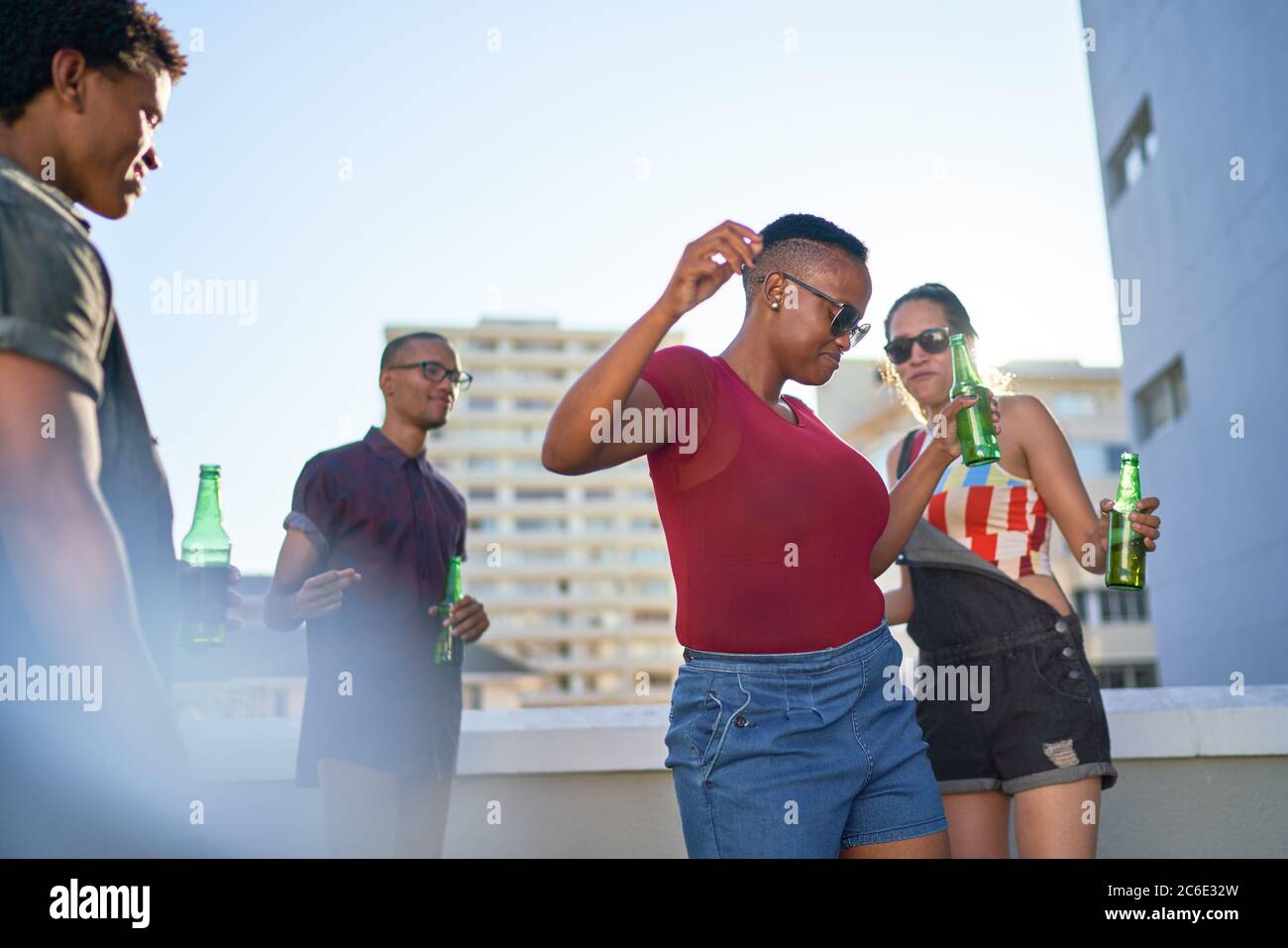 Carefree young friends dancing and drinking beer on urban rooftop Stock Photo