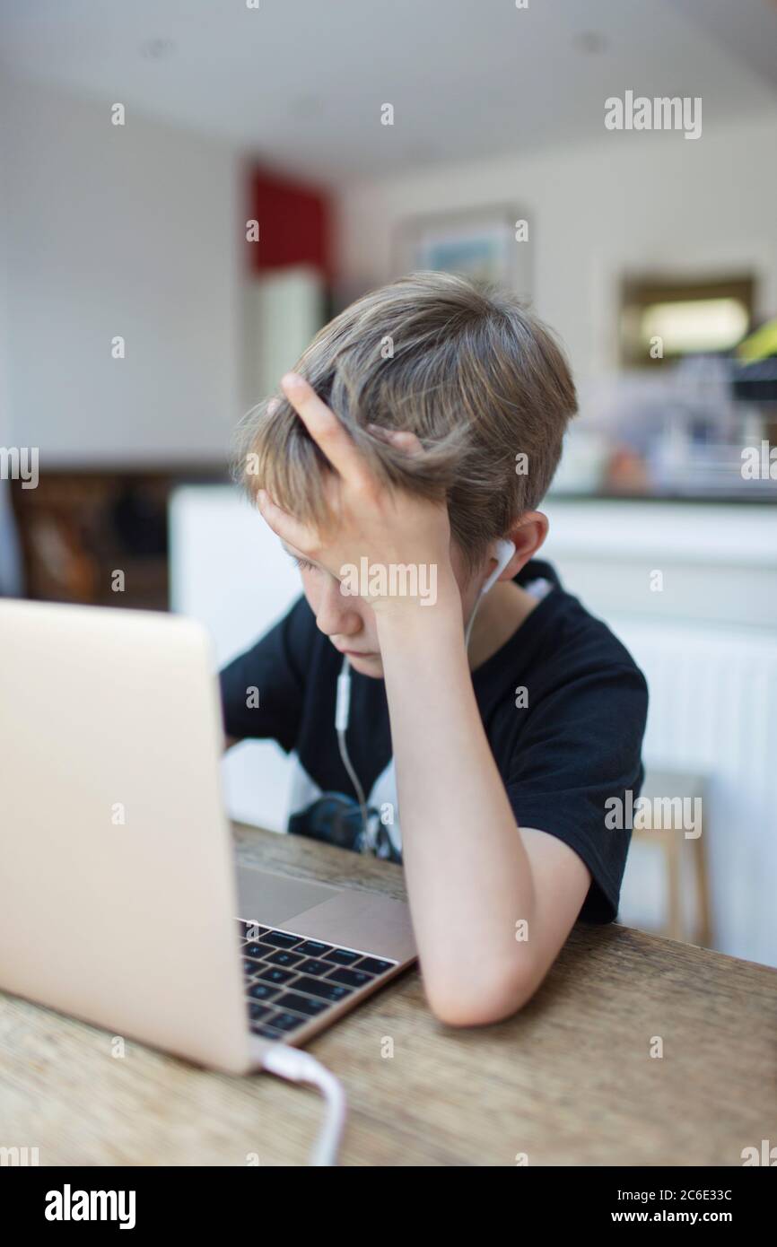 Boy with headphones homeschooling at laptop Stock Photo