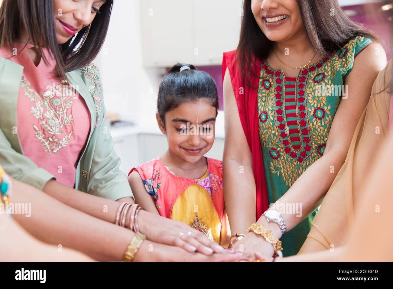 Indian women and girl in saris joining hands Stock Photo