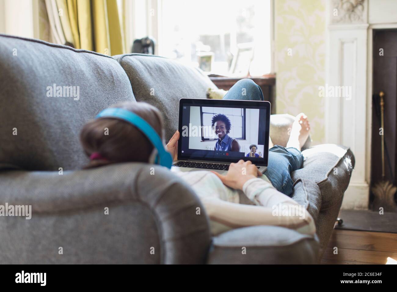 Teenage girl video chatting with friends on living room sofa Stock Photo