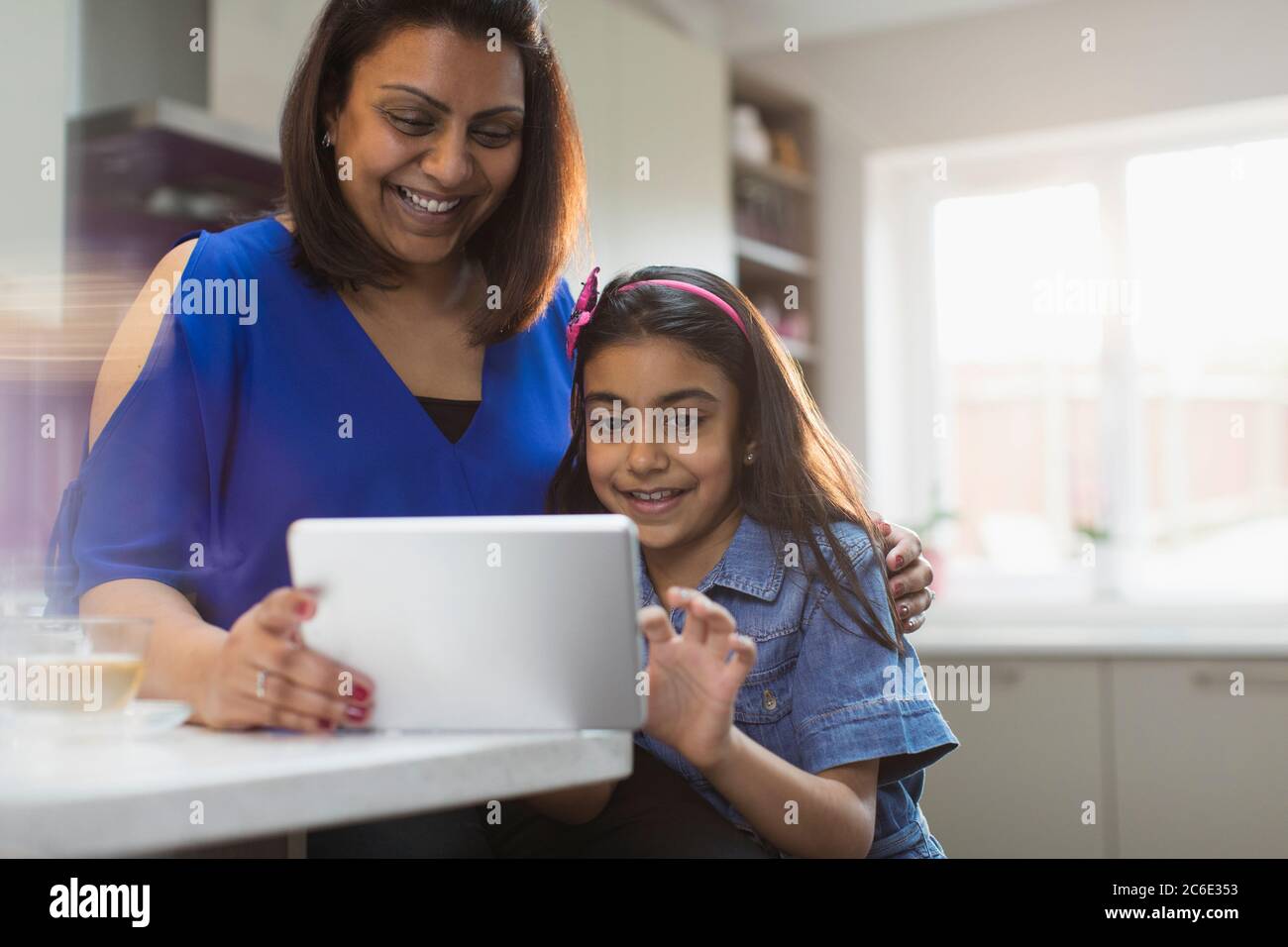 Happy mother and daughter using digital tablet in kitchen Stock Photo