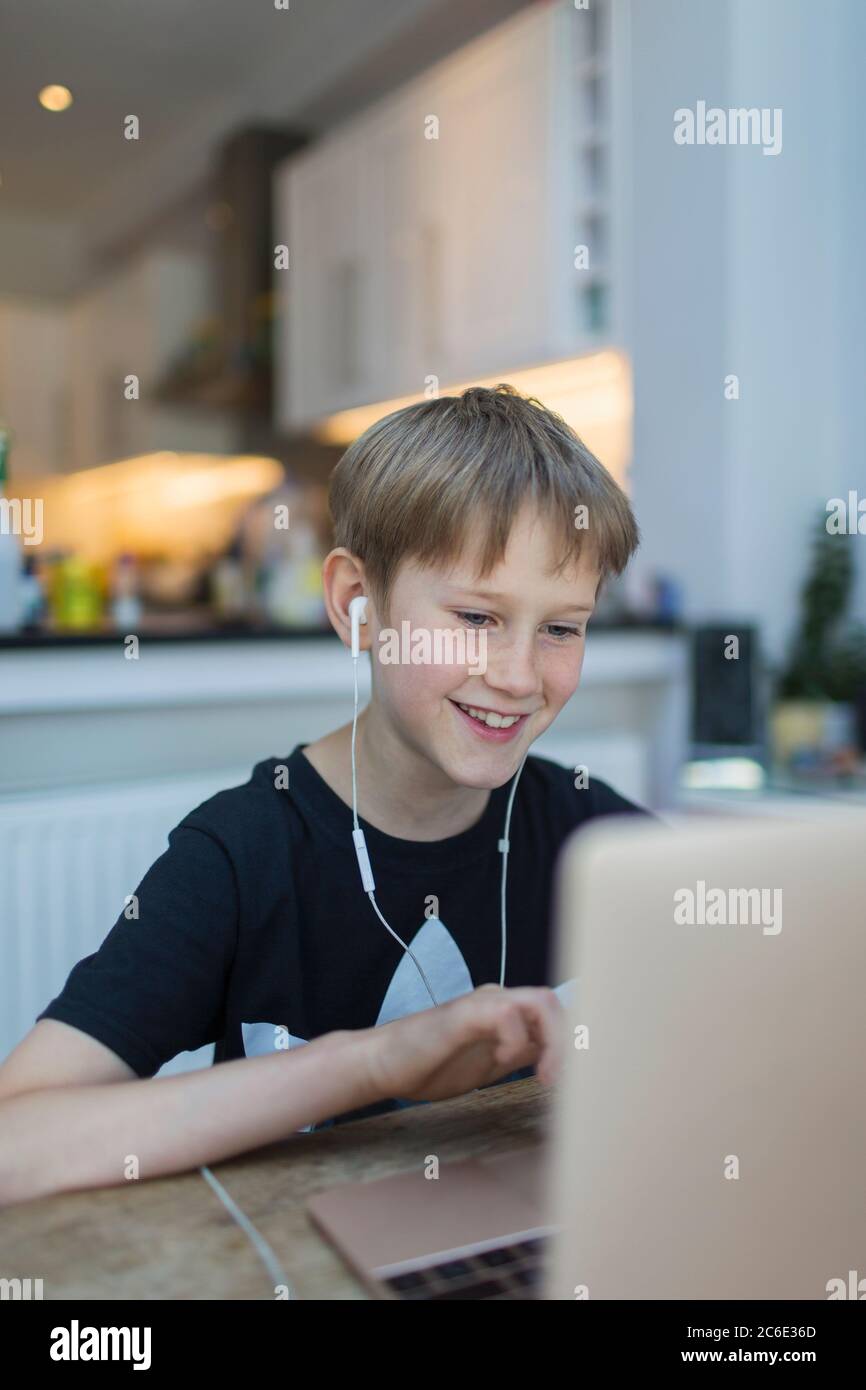 Smiling boy with headphones homeschooling at laptop Stock Photo
