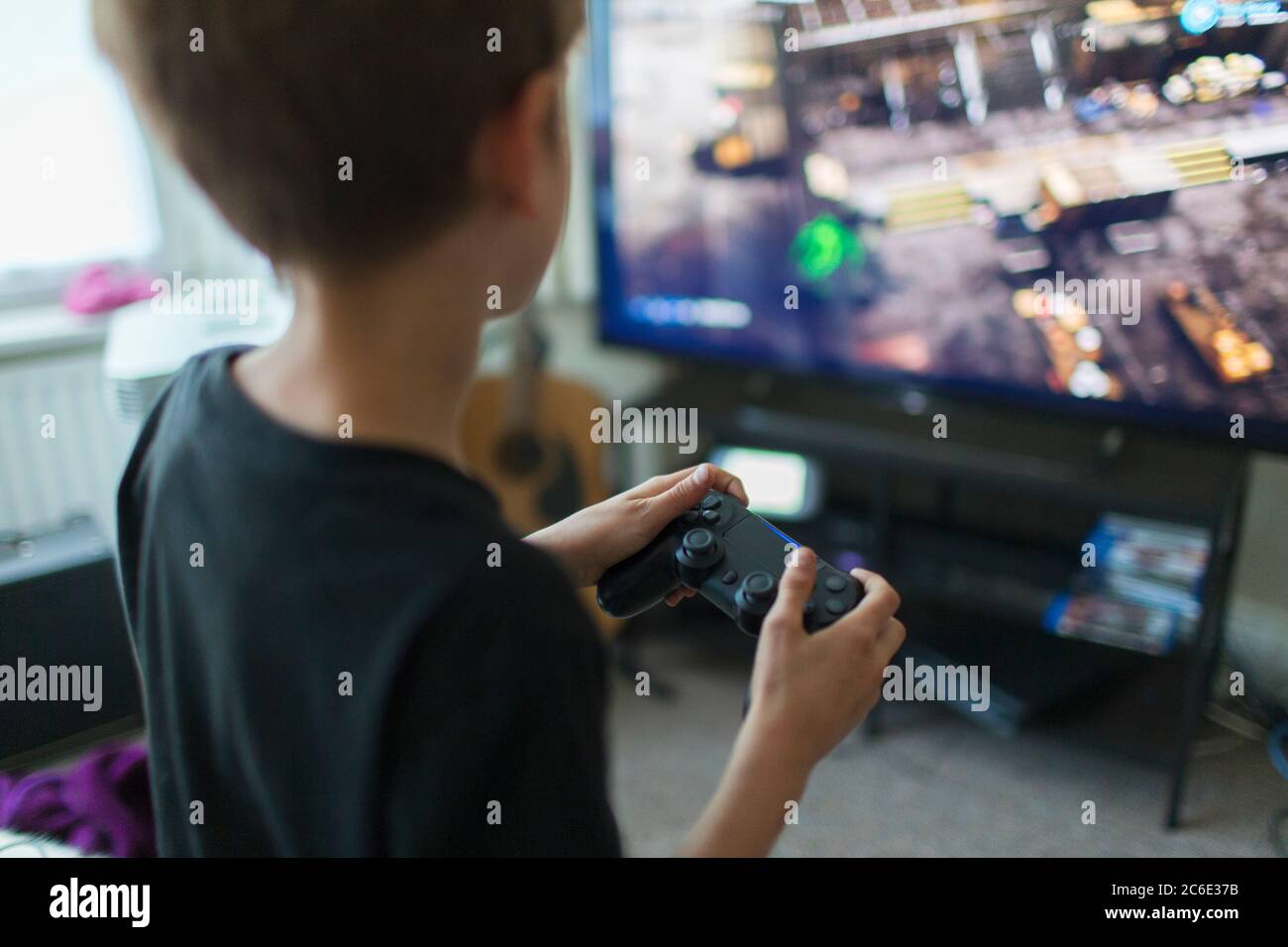 Boy playing video game at TV in living room Stock Photo