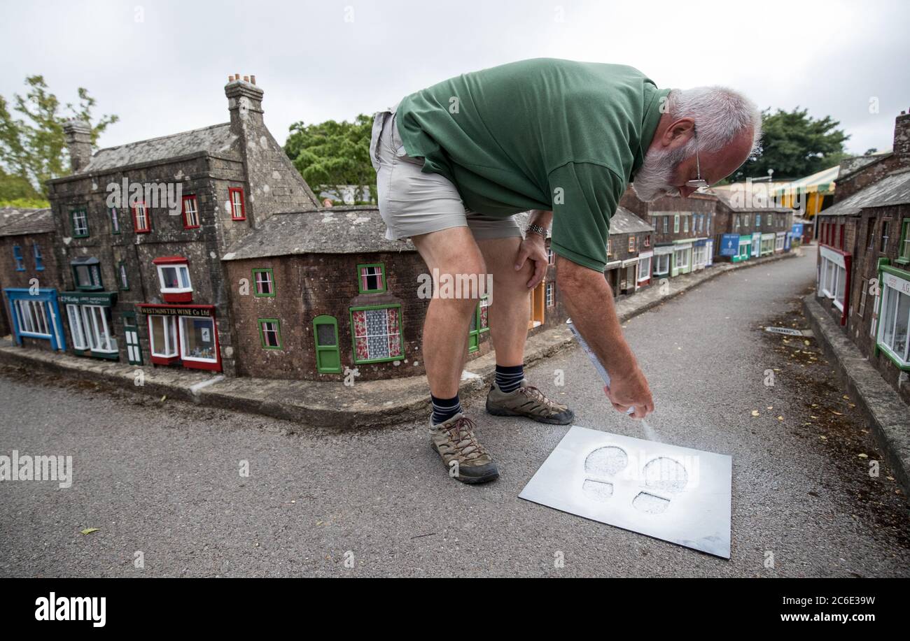 A volunteer spray paints directional footprints on the floor at the Wimborne Model Town and Gardens in Wimborne, Dorset, as they prepare to reopen to members of the public on Saturday following the easing of lockdown restrictions in England. Stock Photo
