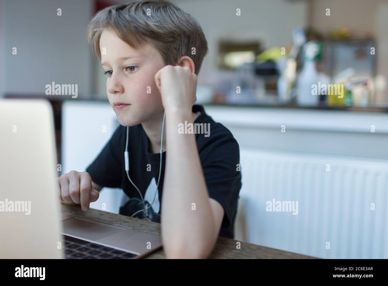 Focused boy with headphones homeschooling at laptop Stock Photo