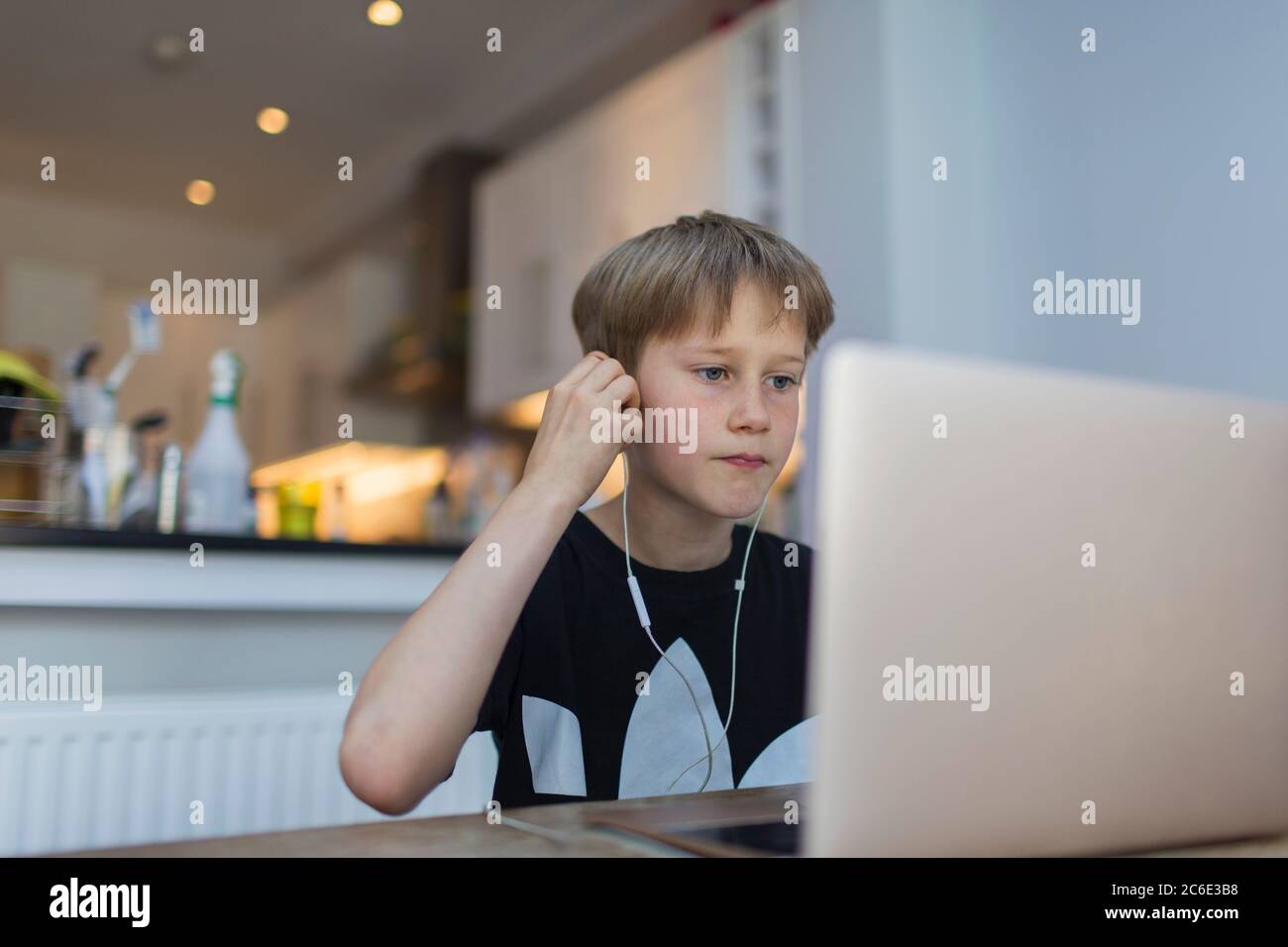 Boy with headphones homeschooling at laptop Stock Photo