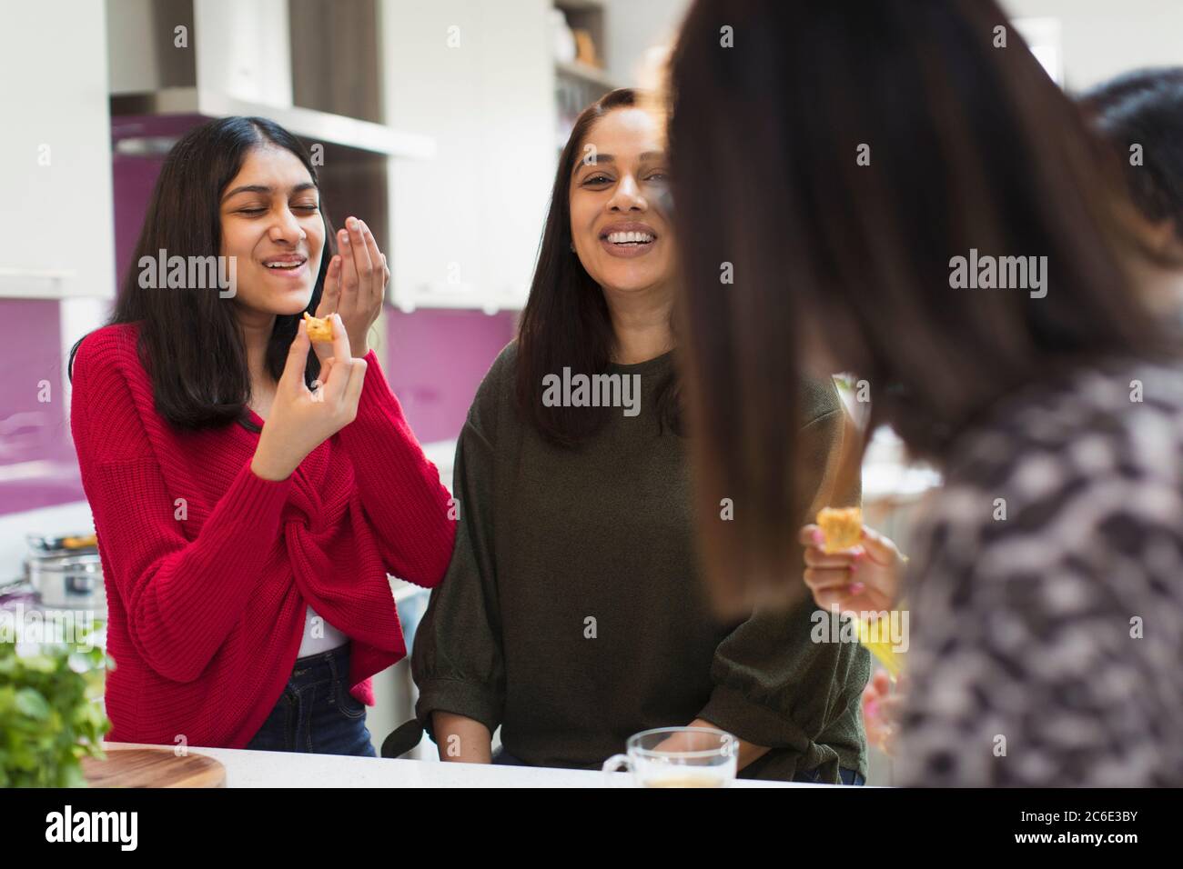 Happy women eating and talking in kitchen Stock Photo