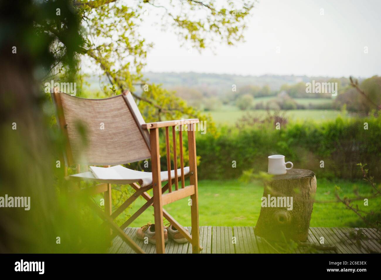 Chair and coffee on tranquil balcony overlooking rural field Stock Photo