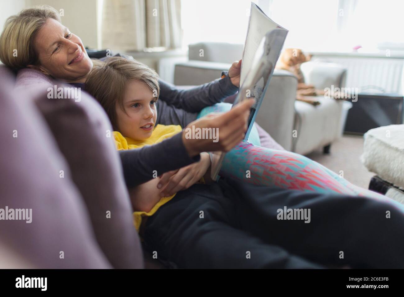 Happy mother and son reading book on living room sofa Stock Photo