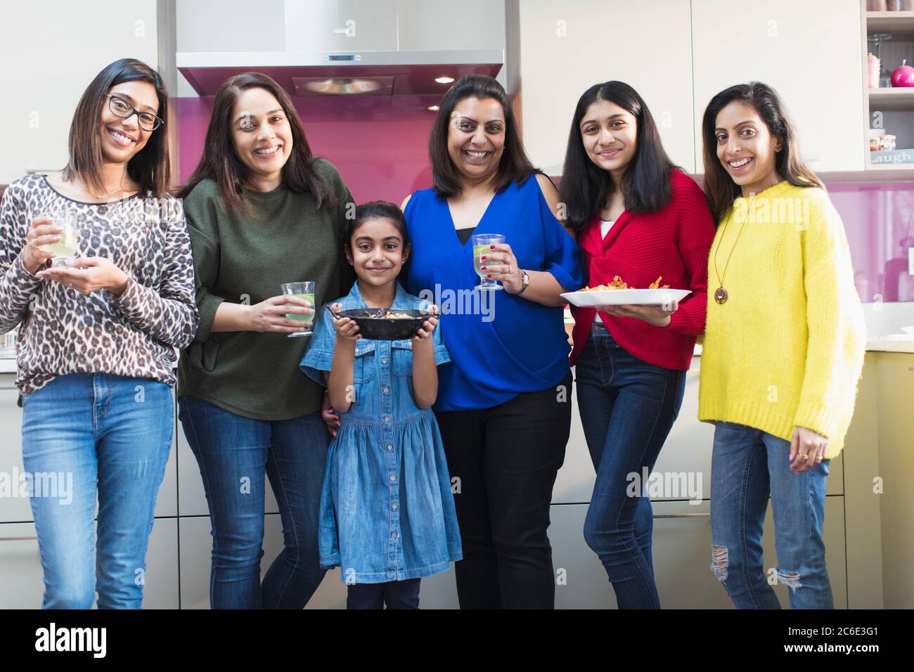 Portrait happy Indian women and girls preparing food in kitchen Stock Photo