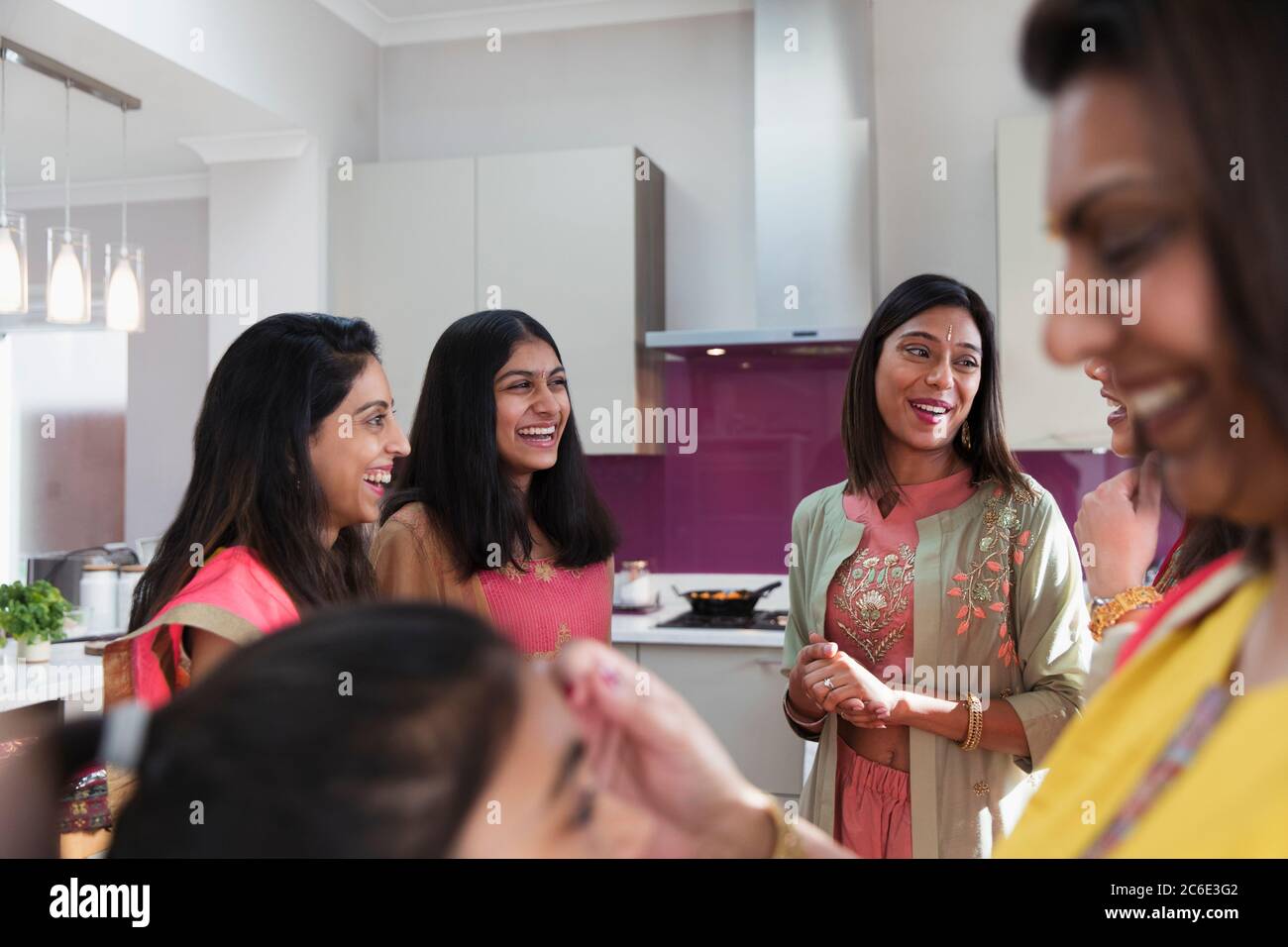 Happy Indian women in saris talking in kitchen Stock Photo