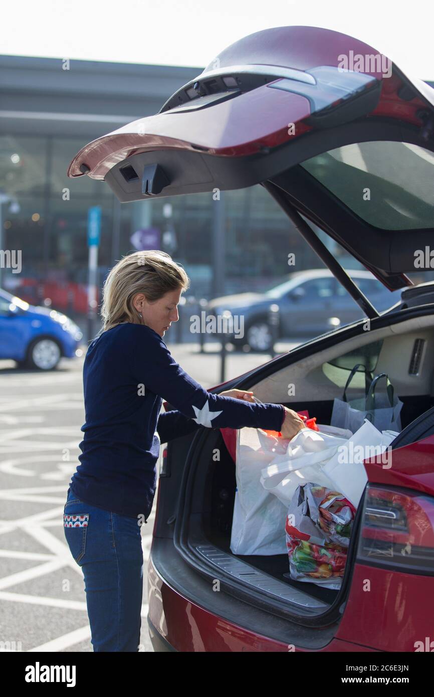 Woman loading groceries into back of car in parking lot Stock Photo