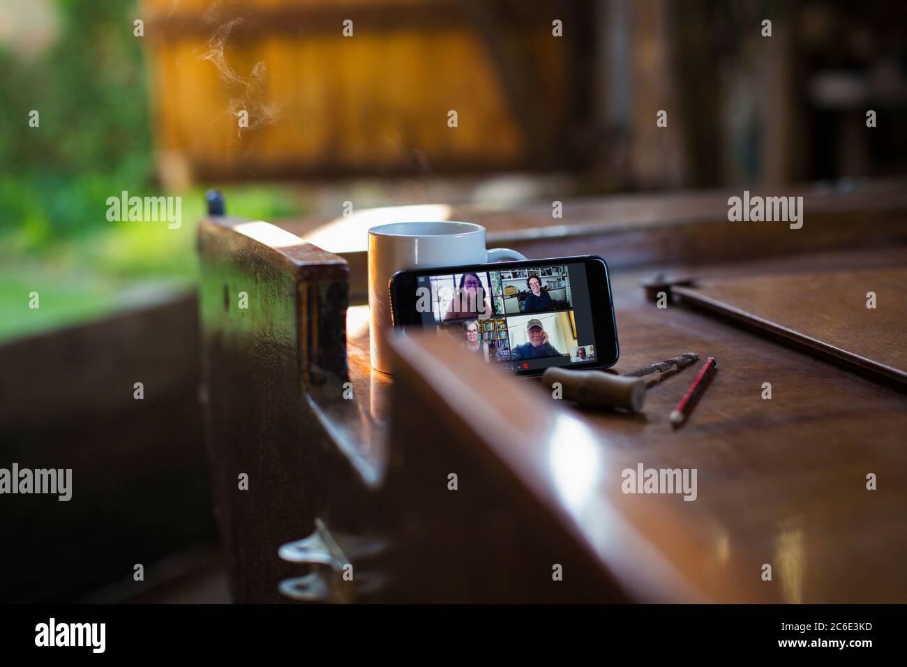 Colleagues video chatting on smart phone screen on wooden boat Stock Photo