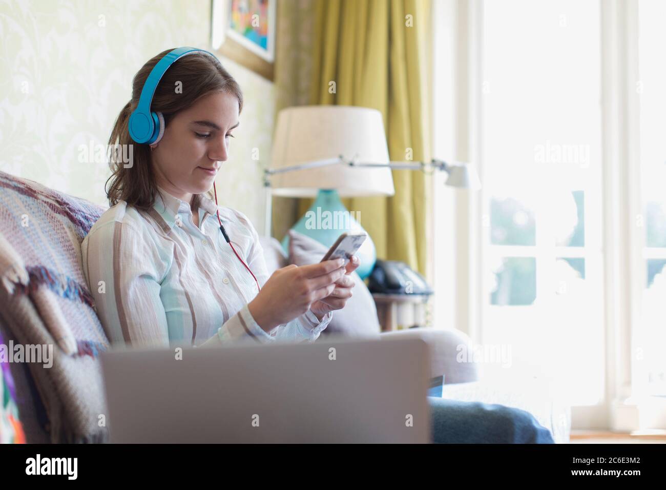 Teenage girl with headphones and smart phone on sofa Stock Photo - Alamy