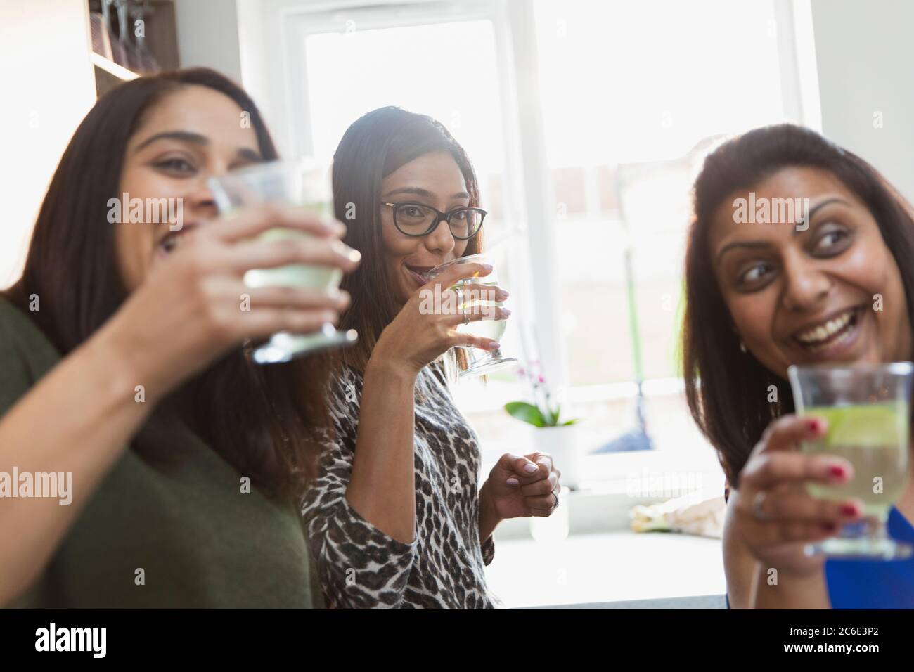 Happy Indian women drinking in kitchen Stock Photo
