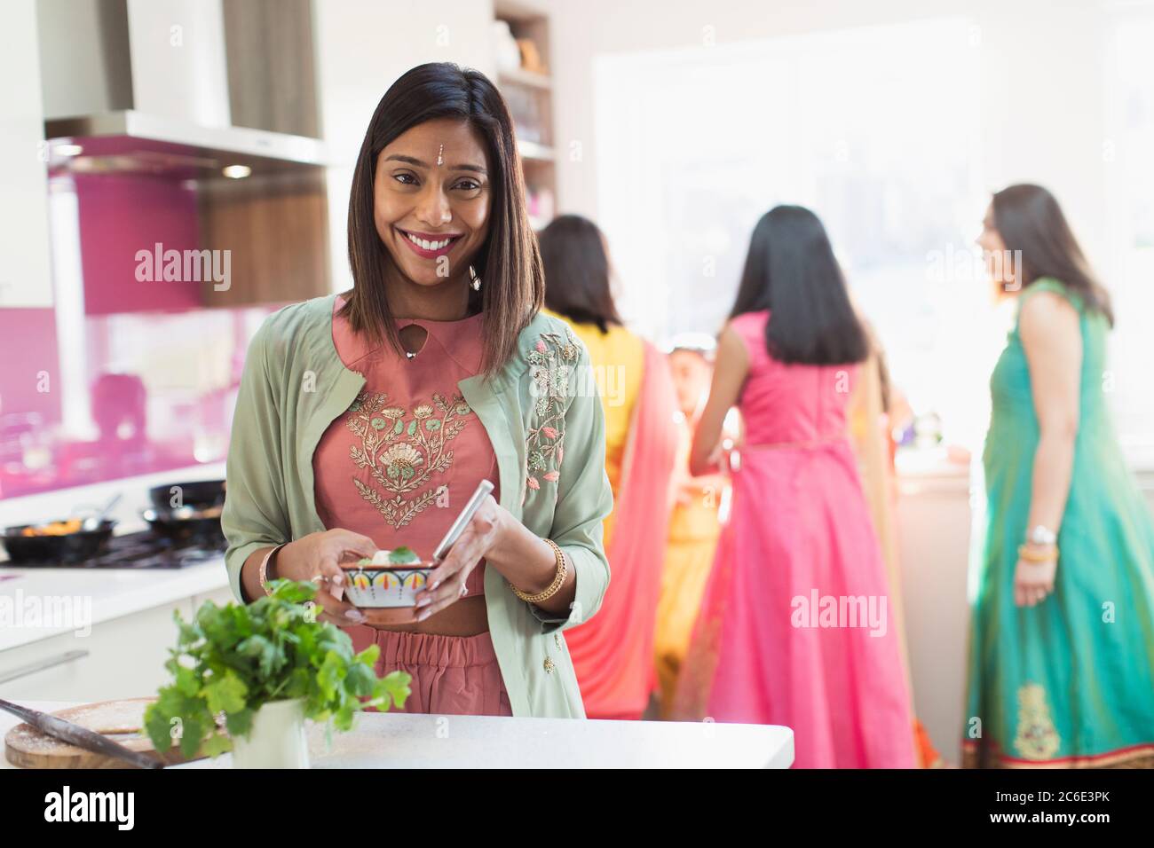 Portrait happy Indian woman in sari and bind cooking food in kitchen Stock Photo