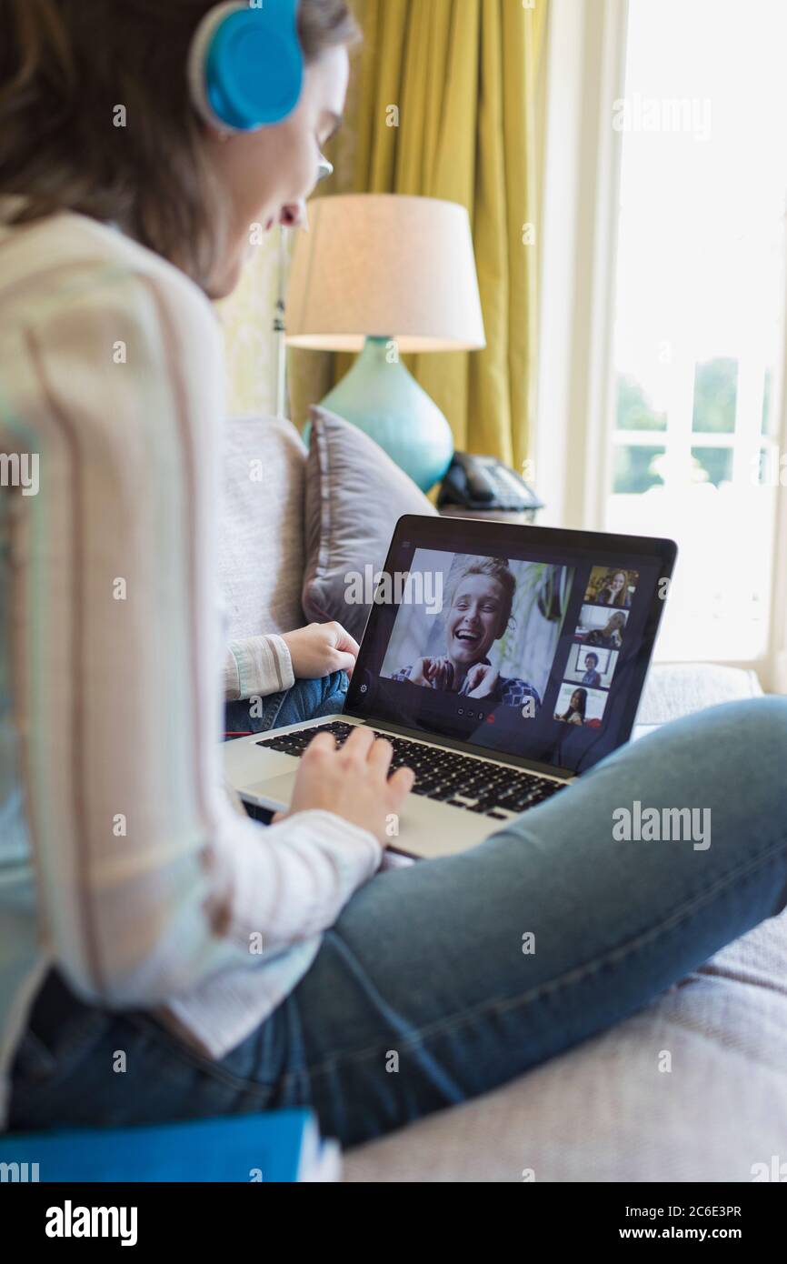 Teenage girl with headphones and laptop video chatting with friends Stock Photo