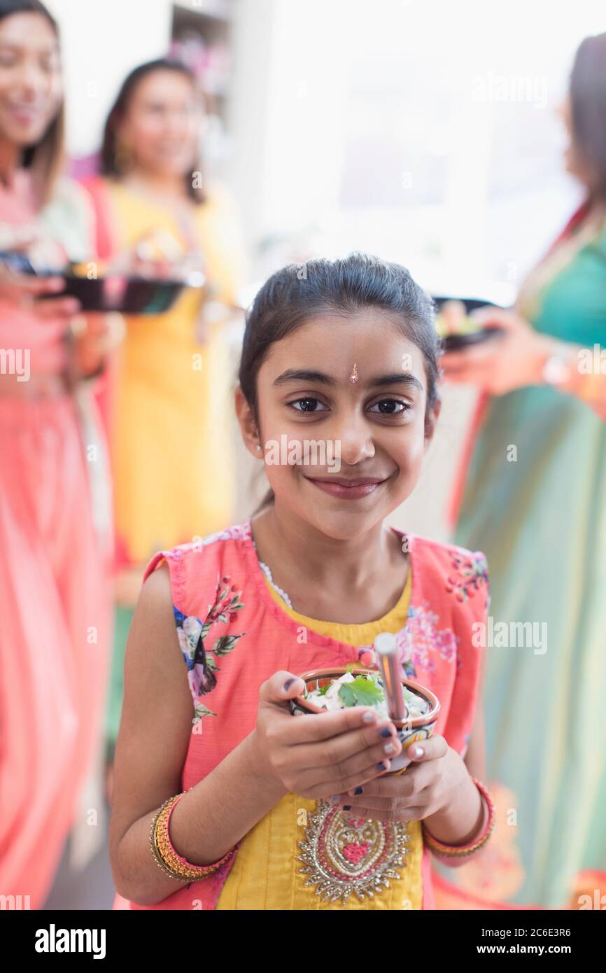 Portrait smiling Indian girl in sari and bind with bowl of rice Stock Photo