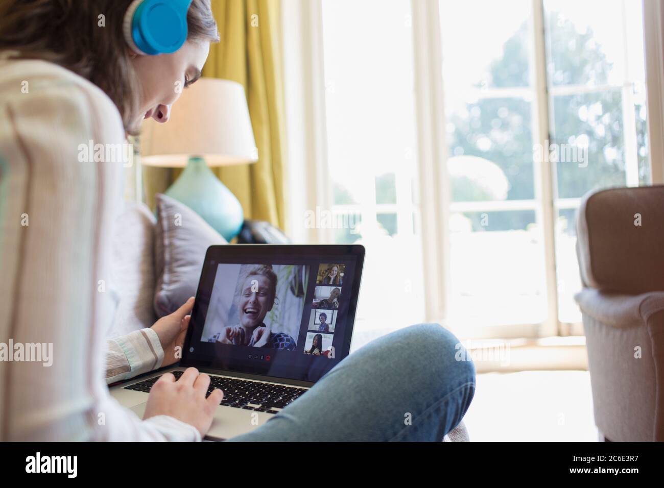 Teenage girl with headphones and laptop video chatting with friends Stock Photo