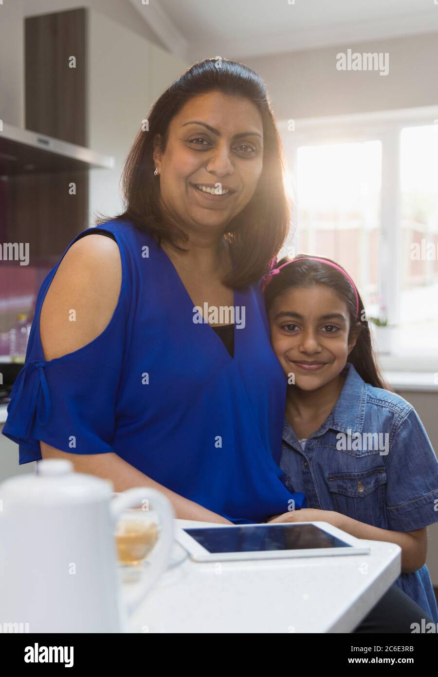 Portrait smiling mother and daughter with digital tablet in kitchen Stock Photo