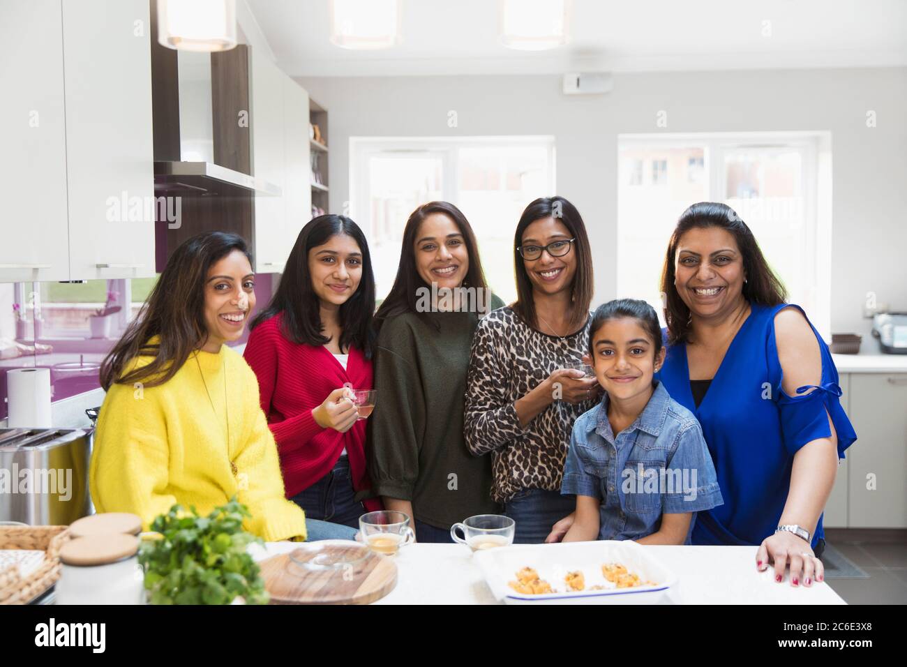 Portrait happy Indian women and girls cooking in kitchen Stock Photo