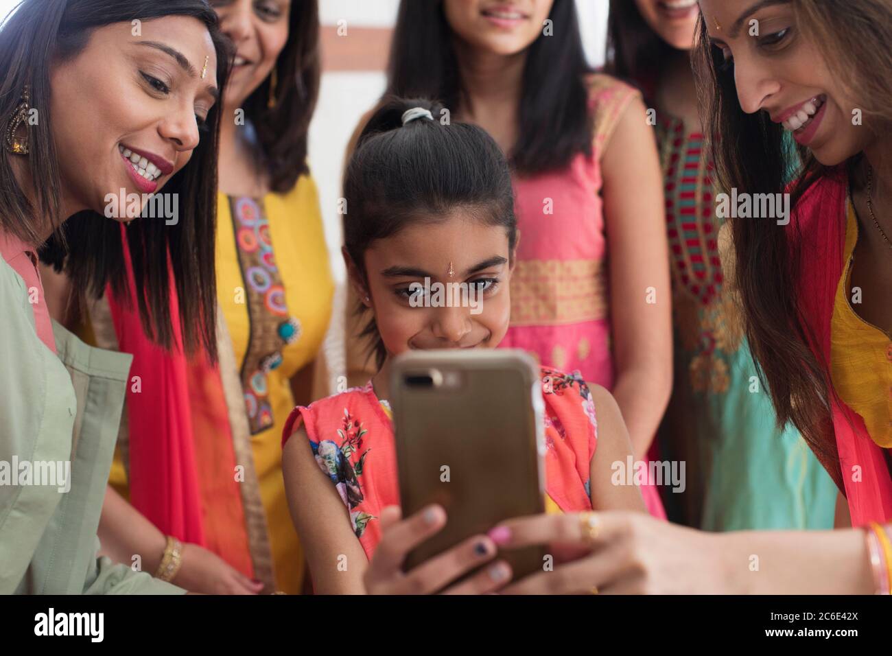 Indian women and girls in saris and bindis using smart phone Stock Photo