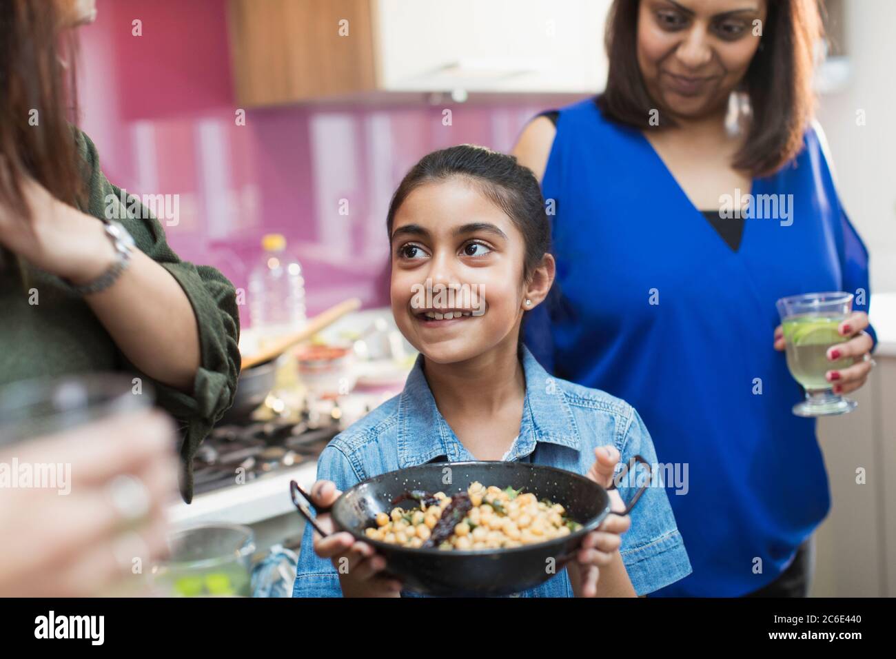 Happy Indian girl with bowl of food in kitchen Stock Photo