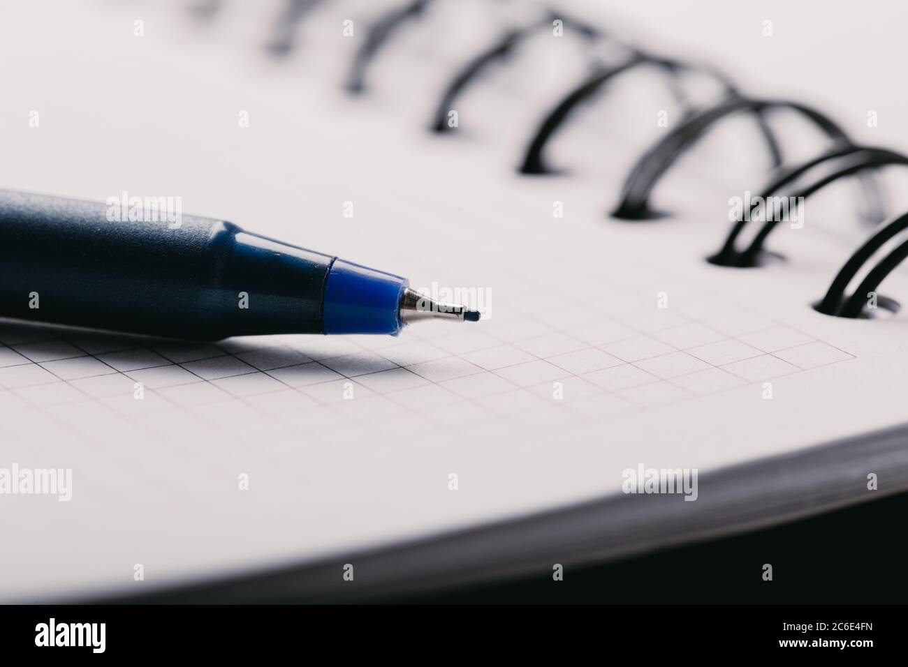 Opened notepad in a cage with an automatic plastic ballpoint pen close-up. Stock Photo