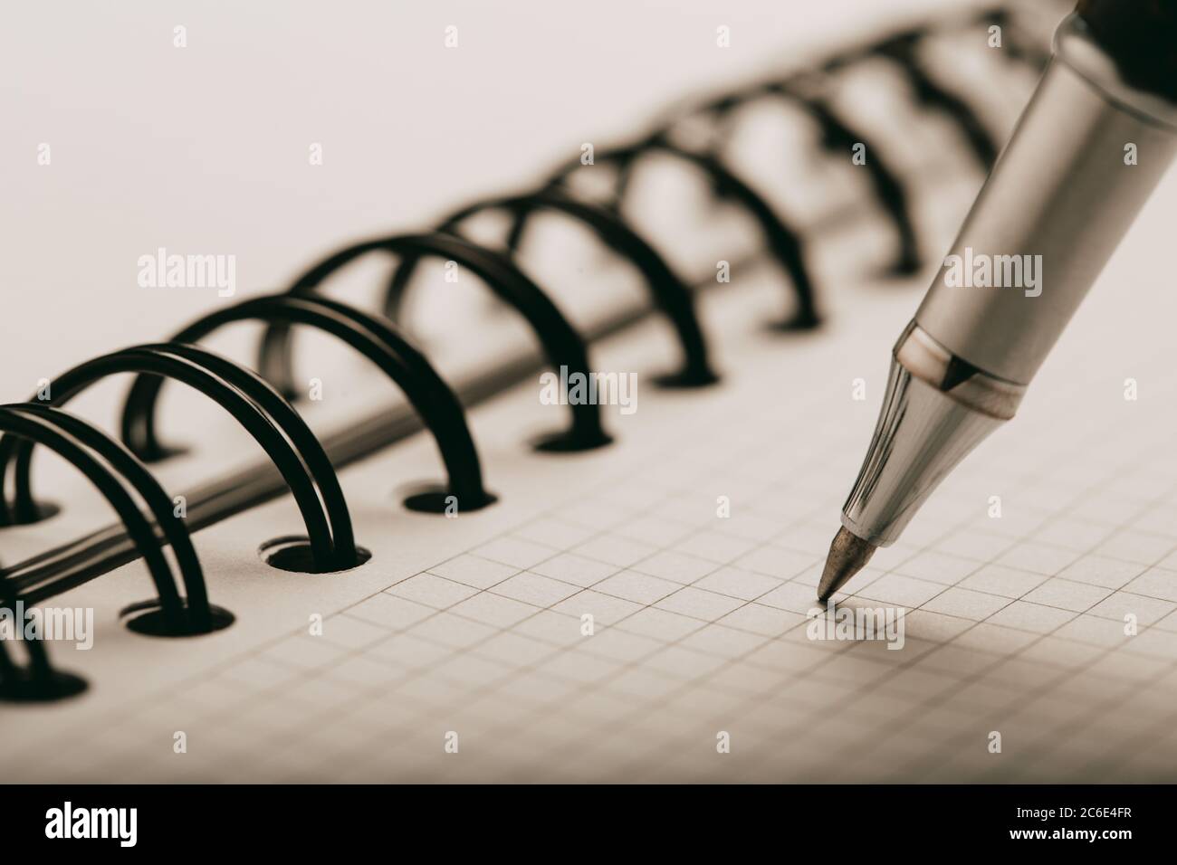 Opened notepad in a cage with an automatic plastic ballpoint pen close-up. Stock Photo
