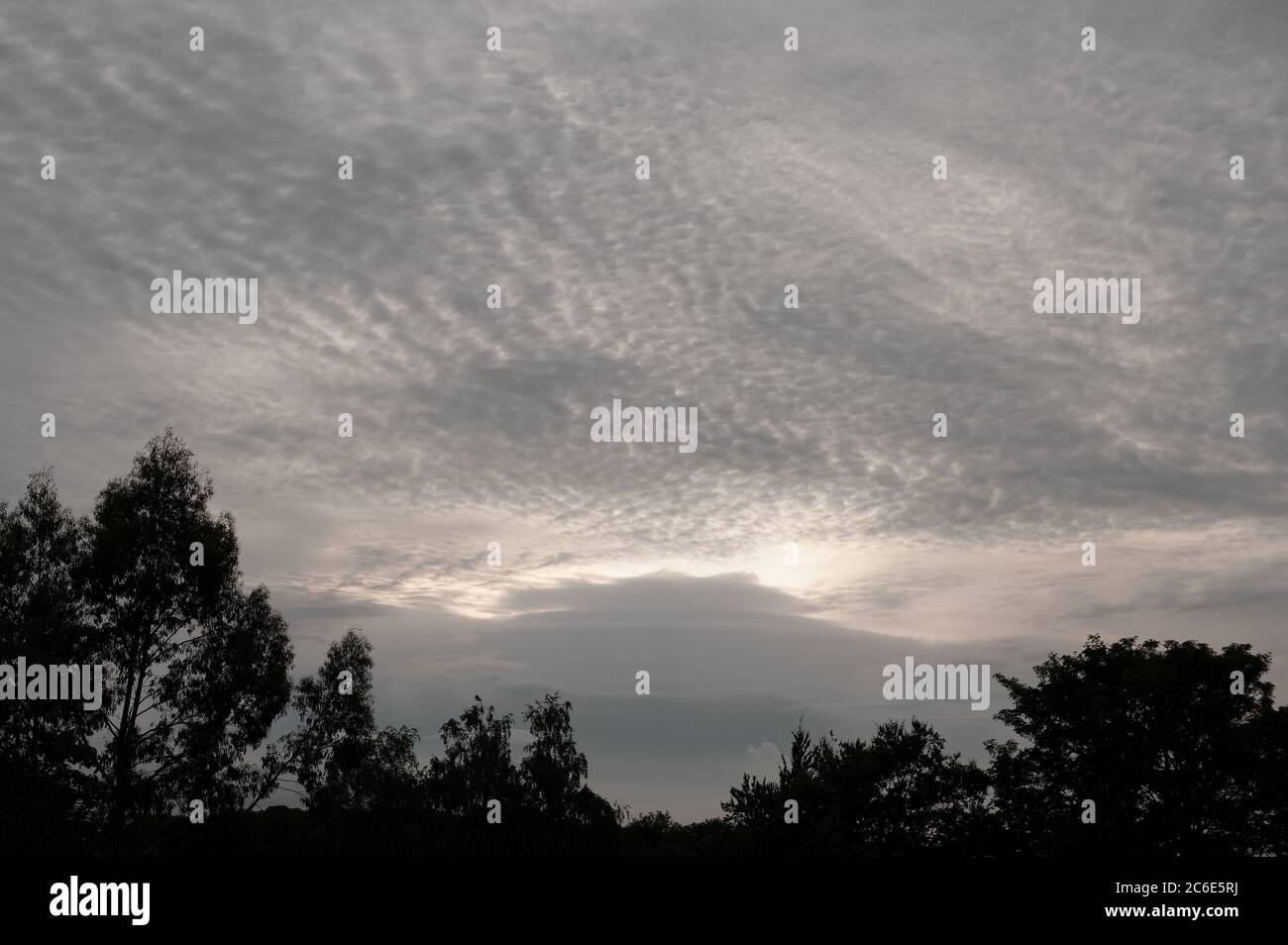 High altitude Altocumulus and lower Nimbostratus on a very grey and over cast skyline before sunset with threatening occluded front moving in Stock Photo
