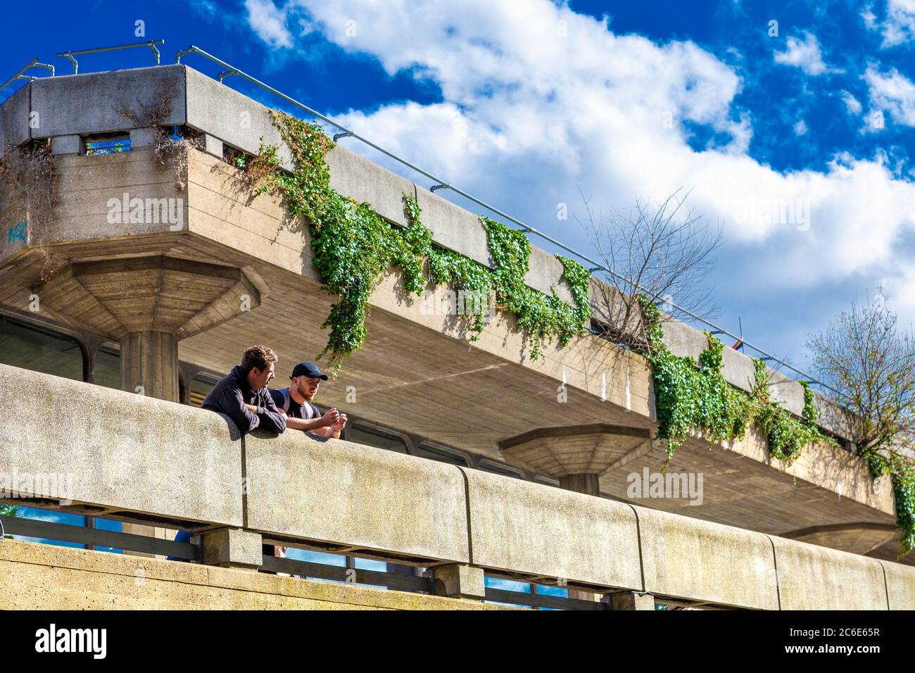 Two men talking on the terrace of brutalist style Queen Elizabeth Hall in Southbank Centre, Southbank, London, UK Stock Photo