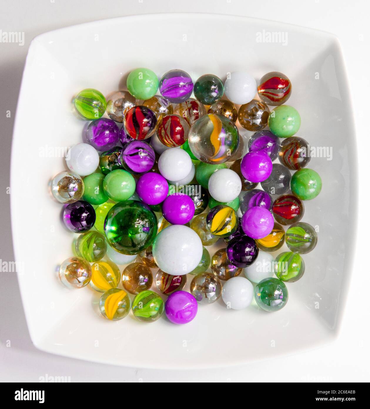Colourful Marbles in a bowl against a white background Stock Photo