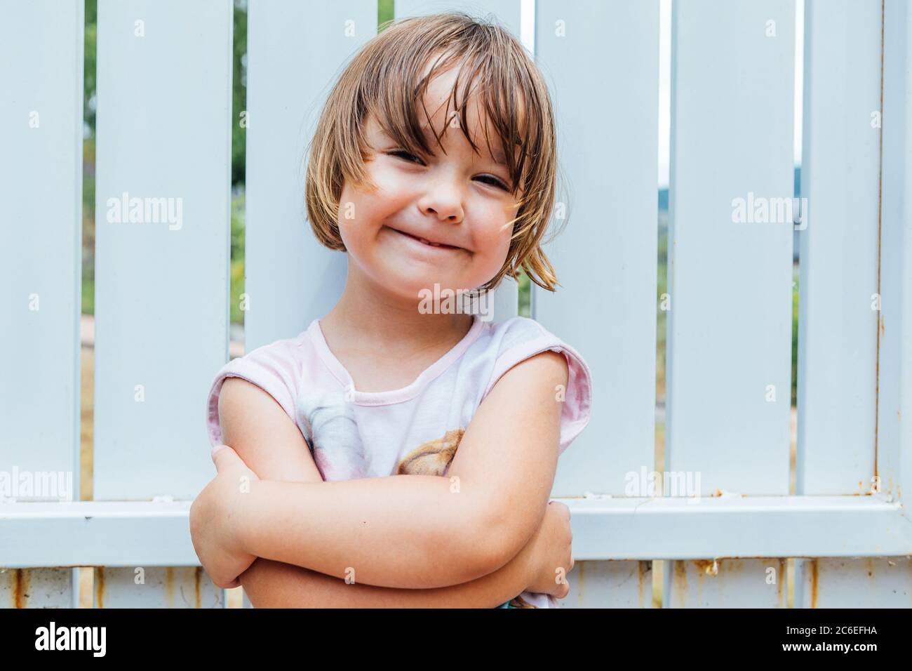 Portrait of blond-haired girl with arms crossed smiling Stock Photo