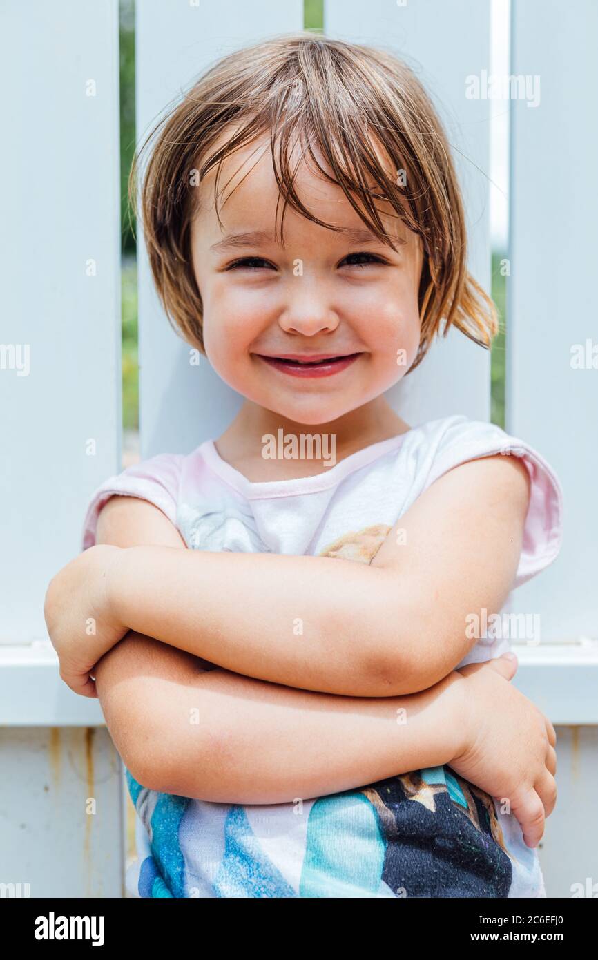 Portrait of blond-haired girl with arms crossed smiling Stock Photo