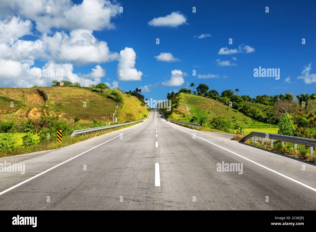 Empty asphalt road through the green field and clouds on blue sky ...